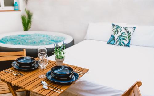 a table with two beds and a tub with plates and glasses at La Calita Escondida - Jacuzzi y Cocina en Terraza Privada - Piscina y Parking Gratis in Chiclana de la Frontera