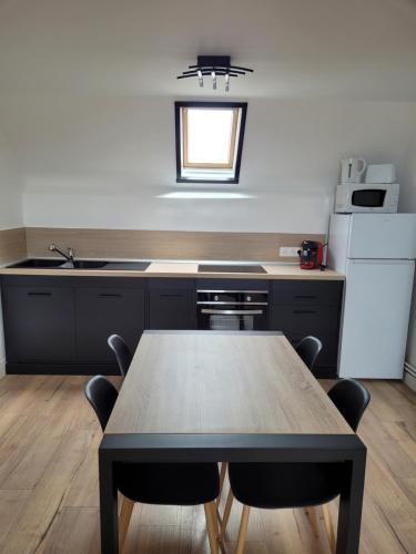 une cuisine avec une table avec des chaises et un réfrigérateur dans l'établissement Le portel plage, à Le Portel