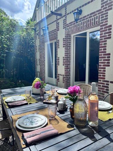 une table en bois avec des assiettes et des fleurs dessus dans l'établissement Exceptional 5 bedroom house near the beach, à Trouville-sur-Mer