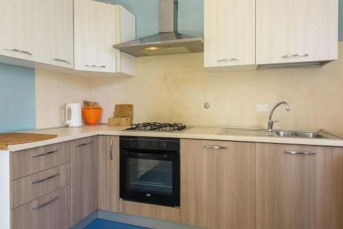 a kitchen with white cabinets and a black stove top oven at Golden Luxe - Roman Luxury Villa in the Sea in Camaiore