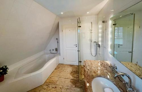 a bathroom with a tub and a shower and a sink at Teil "Carpe Diem" in Rantum