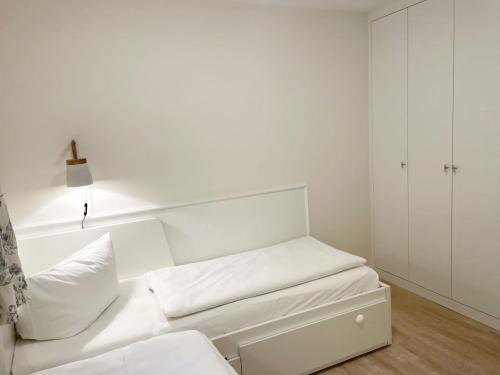 a white room with a bed and a white cabinet at Landhaus auf der Düne, App 4 in Rantum
