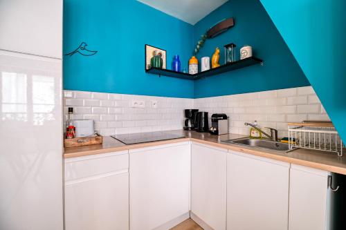 une cuisine avec des armoires blanches et un mur bleu dans l'établissement Le Cocon de Jeanne, à Rouen