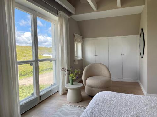 a bedroom with a chair and a large window at Strandhaus in Rantum