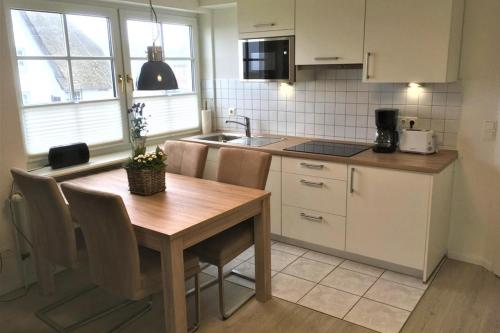 cocina con mesa de madera con sillas y fregadero en Thora Jaiken Hüs Thora Jaiken, Apart Eike, en Rantum
