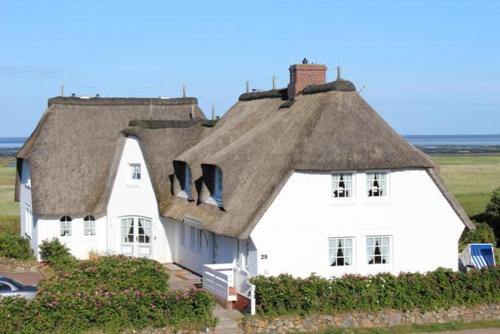 a large white house with a thatched roof at Heefkant Haus Heefkant,HK 02 in Rantum