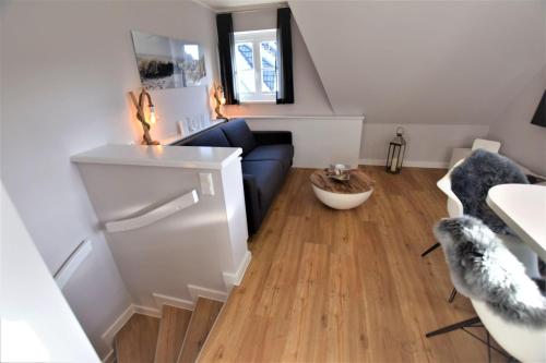 a living room with a blue couch and wooden floors at Warfthüs App 08 in Rantum