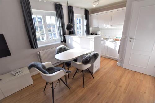 a kitchen with a white table and chairs in a room at Warfthüs App 08 in Rantum
