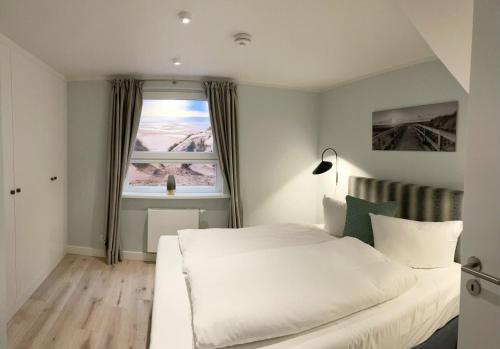 Un dormitorio con una cama blanca y una ventana. en Warfthüs, App 1, en Rantum