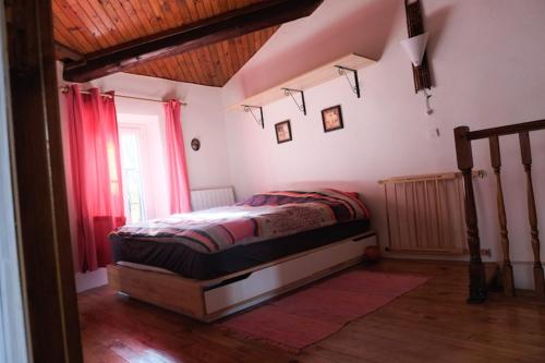 - une chambre avec un lit dans une pièce dotée de rideaux rouges dans l'établissement Charmante Maison de Village dans les fenouilledes, à Cassagnes