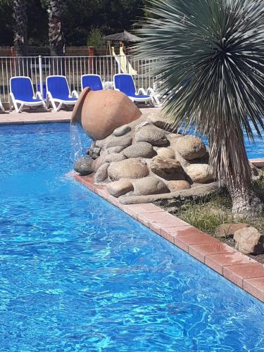 a swimming pool with a fountain and chairs and a palm tree at mobilhome argeles in Argelès-sur-Mer
