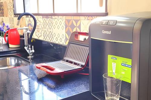 a kitchen counter with a cash register next to a sink at Apartamento 15 - (850 mt do Centro) - 2 Banheiros in Poços de Caldas