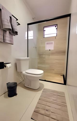 a bathroom with a toilet and a glass shower at Apartamento 15 - (850 mt do Centro) - 2 Banheiros in Poços de Caldas