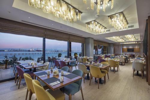 Un restaurante con mesas y sillas y un gran ventanal. en Holiday Inn Istanbul - Tuzla Bay by IHG, en Estambul