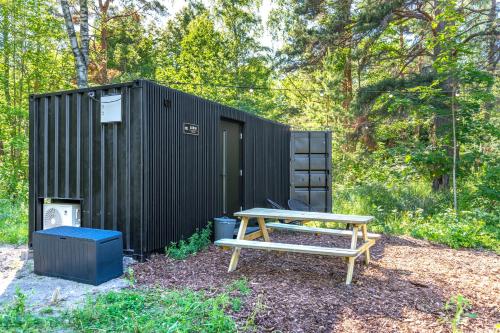a picnic table and a bench in front of a black shed at Chic Sauna Cabin Near the Sea - SABIN Cabin Nº04 in Tsitre