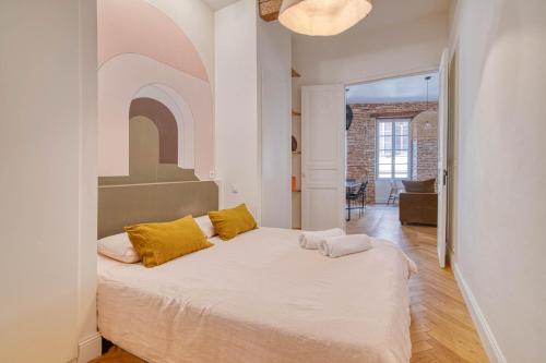 - une chambre avec un grand lit blanc et des oreillers jaunes dans l'établissement Chez Pauline & Simon - Appt climatisé, à Toulouse