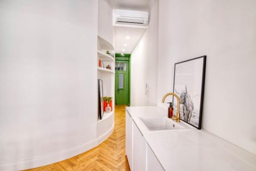 une salle de bain blanche avec un lavabo et une porte verte dans l'établissement Chez Pauline & Simon - Appt climatisé, à Toulouse