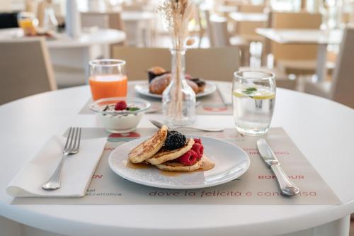 a white table with a plate of food on it at Hotel Universal in Cattolica
