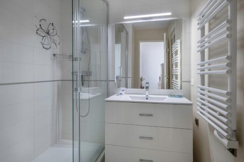 a white bathroom with a sink and a shower at Bord de mer, rez-de-terrasse pour 4, Pornic in La Birochere