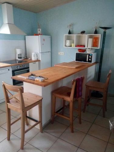 - une cuisine avec un comptoir en bois et 2 chaises dans l'établissement maison récente proche forêt et bord de mer, à Saint-Jean-de-Monts