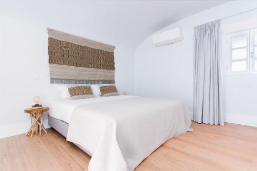 a white bedroom with a large bed and a window at Limehome Evora Rua de Machede 52 in Évora