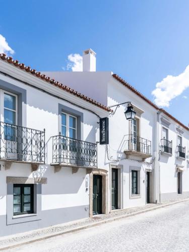 a white house with balconies on a street at Limehome Evora Rua de Machede 52 in Évora