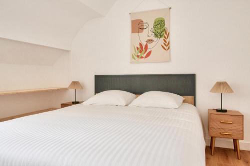 une chambre avec un grand lit blanc et deux lampes dans l'établissement À 230m de la plage - Bel appartement pour 4, à Fouesnant