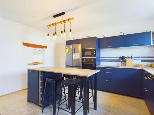 a kitchen with blue cabinets and a island with bar stools at A 180m du bord de mer, maison pour 11 in Saint-Clément-des-Baleines
