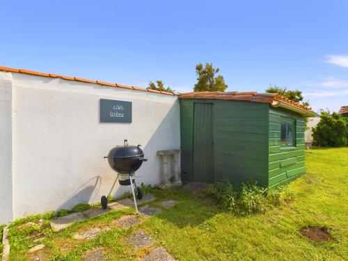 a green shed next to a white building with a grill at A 180m du bord de mer, maison pour 11 in Saint-Clément-des-Baleines