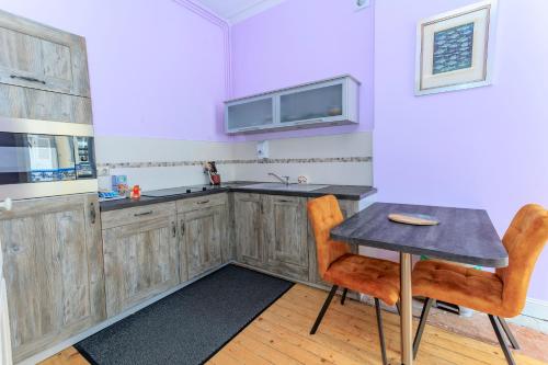 une cuisine avec des armoires en bois et une table et des chaises dans l'établissement Le NID D'ORIENT, à Cherbourg en Cotentin