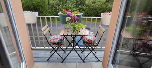 a table and chairs on a balcony with flowers at Mon petit paradis - Proche de la mer et Touquet in Camiers