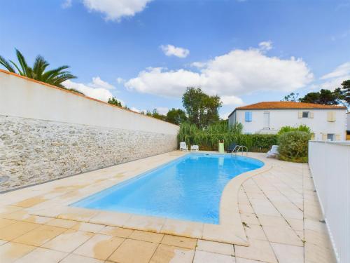 une piscine dans une arrière-cour avec un mur en pierre dans l'établissement Maison pour 7, piscine collective, 2km de la plage, à Les Sables-dʼOlonne