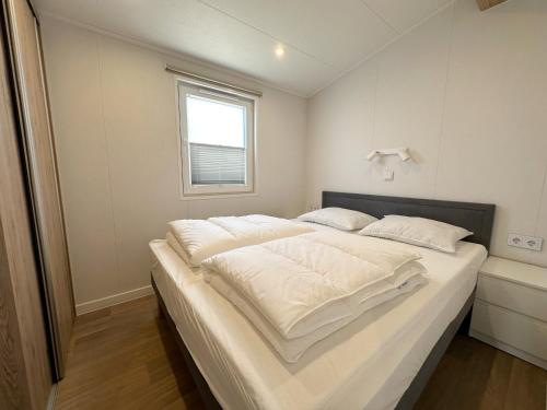 a large white bed in a room with a window at Chalet 501b op Recreatiepark De Wielen in Sint Maarten