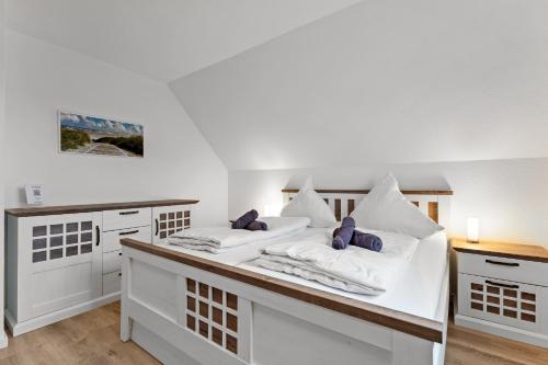 a white room with two beds with purple pillows at Schonergang Greetje Oog in Krummhörn