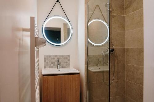 une salle de bain avec un lavabo et une douche avec un miroir dans l'établissement Gîte Familial au cœur des vignes, à Béziers