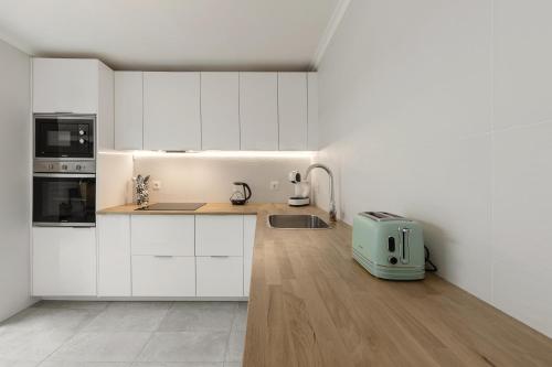 una cucina con armadi bianchi, lavandino e tostapane di Casa do Alecrim a Óbidos