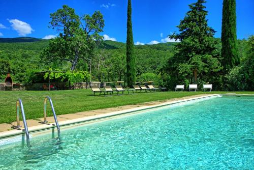 a swimming pool in a park with chairs and trees at Poggiolino by PosarelliVillas in Chitignano