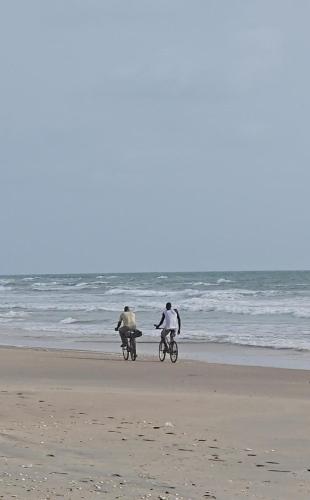 two people riding bikes on the beach at Eden Garden Tujereng gambia in Sanchaba