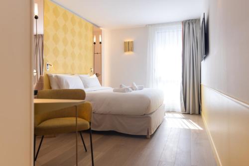 a hotel room with a bed and a chair at Hôtel Kyriad Prestige Paris Asnieres in Asnières-sur-Seine