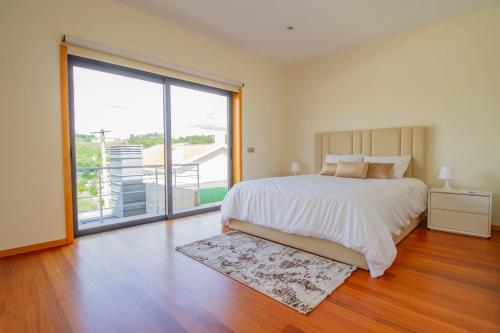 a bedroom with a large bed and a large window at Casa do Douro& Porto in Lousada