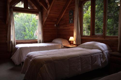 two beds in a room with two windows at Cocos Cura Casas de montaña in San Carlos de Bariloche