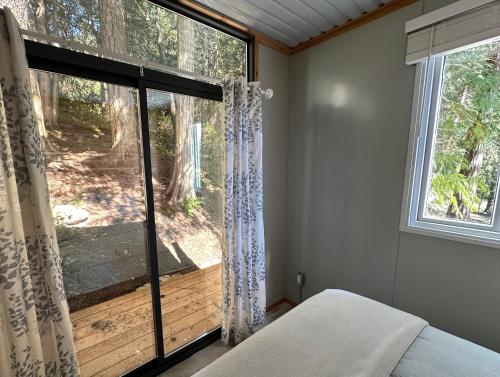 a bedroom with a window with a view of the woods at Thetis Island Get Away Cottage in North Galiano