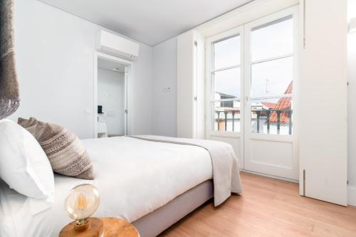 a white bedroom with a bed and a window at Limehome Evora Rua de Machede 61 in Évora