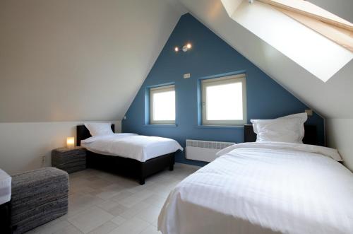una camera mansardata con 2 letti e pareti blu di Back2Front a Boezinge