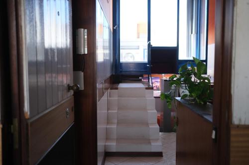 a hallway with a staircase leading to a room with windows at Comprensorio Olivetti - La Serra - stanza 204 in Ivrea