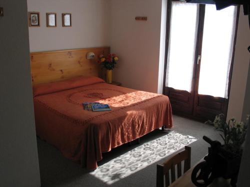 a bedroom with a bed with a red bedspread and a window at Hotel & Restaurant Saint Nicolas Gran Paradiso in Saint Nicolas