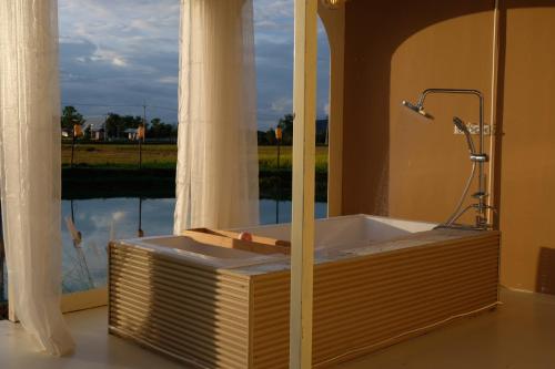 a bath tub in a room with a large window at นานาก๋างโต้ง คาเฟ่&Glamping in Ban Hua Hin