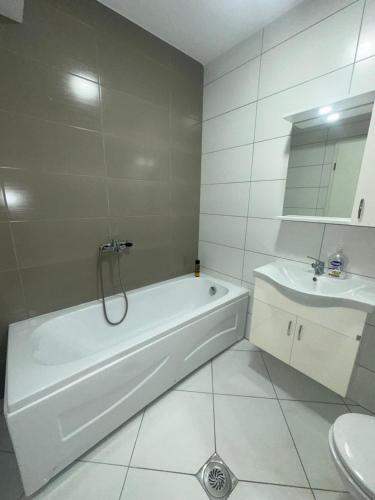 a white bathroom with a tub and a sink at Design Prishtina Apartment 1 in Pristina