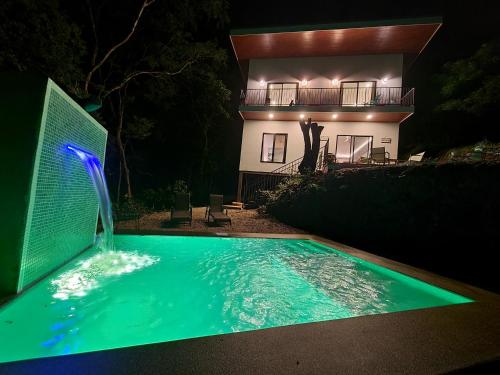 a house with a swimming pool in front of a house at night at Pinilla Highlands Incredible mountain views in Tamarindo