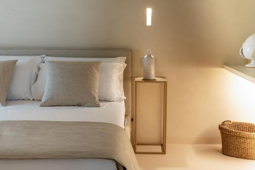 a bed with white pillows and a bottle on a table at NEW OPENING - Palazzo Gasparino Suites in Monopoli